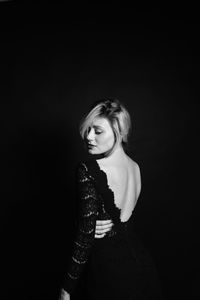 Portrait of woman standing against black background