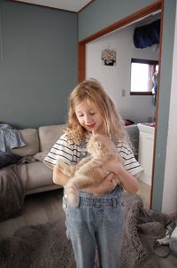 A girl is holding a cream coloured siberian kitten in her arms