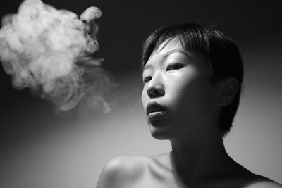 Portrait of woman smoking against wall