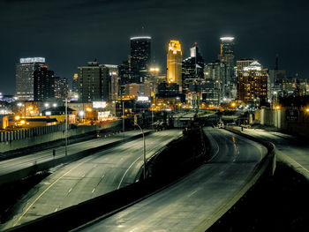 High angle view of illuminated street amidst buildings in city at night