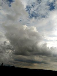 Low angle view of storm clouds over silhouette landscape