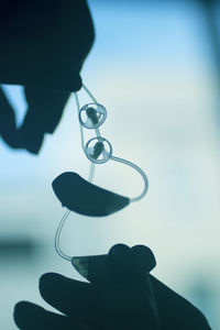 Close-up of silhouette hand holding eyeglasses