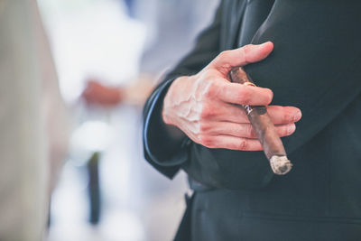 Low section of man holding cigar