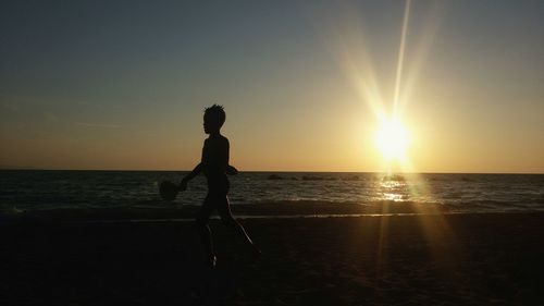 Silhouette man on beach against sky during sunset