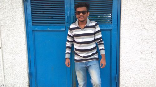 Portrait of young man standing against blue wall