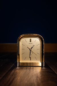 Close-up of clock on table against dark background