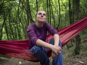 Young woman sitting on hammock in forest