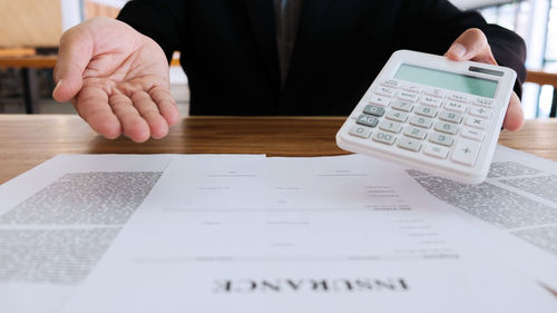 Midsection of man holding paper with text on table