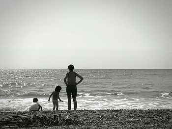 Boys standing on beach against clear sky