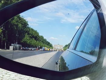 Close-up of side-view mirror against sky