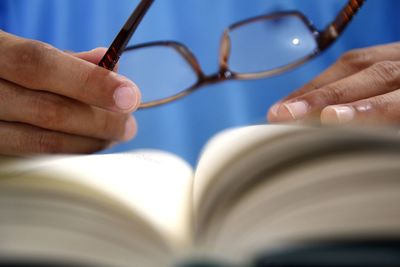 Close-up of hand holding eyeglasses on book