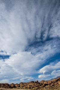 Low angle view of arid landscape against sky filled with cloud formations