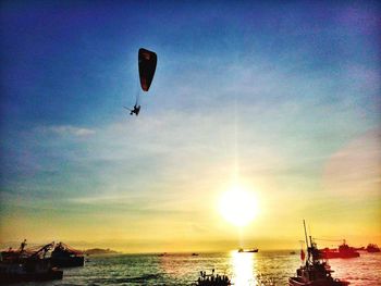 Silhouette people by sea against sky during sunset