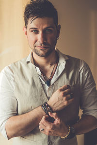 Portrait of smiling young man standing against wall