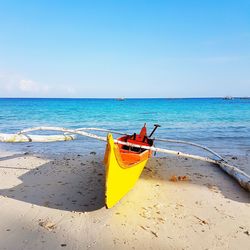 Boat moored on beach against sky