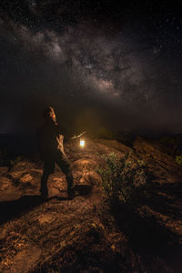 Man with lantern standing against sky at night