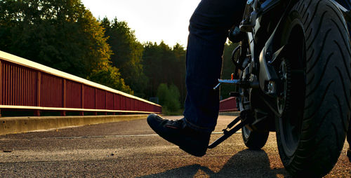 Low section of man riding motorcycle on road