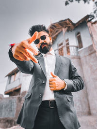 Portrait of young man wearing sunglasses while standing against wall