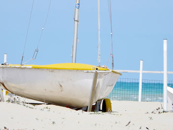 Sailboat moored on beach against clear blue sky