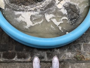 Low section of person standing by water