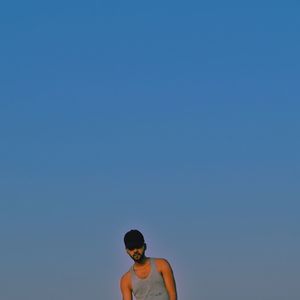 Low angle portrait of young man against clear sky at dusk