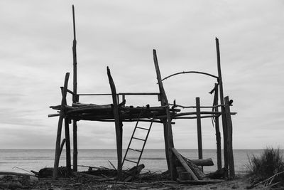 Wooden posts on beach against sky