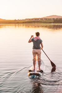 Young woman stand up paddling sup at sunset, lake wallersee, austria