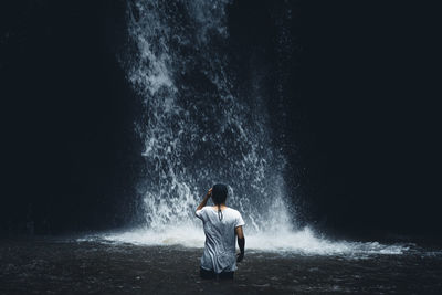 Rear view of man splashing water at night