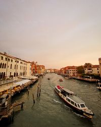 Boats in canal amidst buildings in city against clear sky