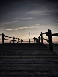 Pier on sea against cloudy sky