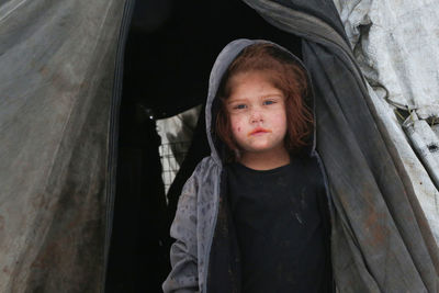 A syrian refugee child at the door of his snow covered tent