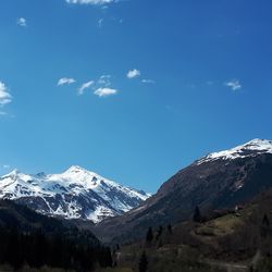 Scenic view of snowcapped mountains against blue sky