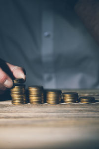 Close-up of hand holding coins on table