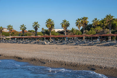 Empty deck chairs and wooden parasols arranged on sandy beach