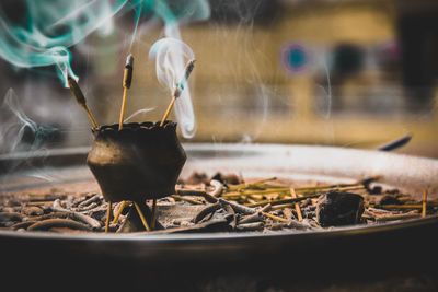 Close-up of burning incenses amidst smoke