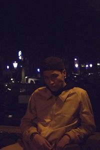 Portrait of man sitting in illuminated city at night