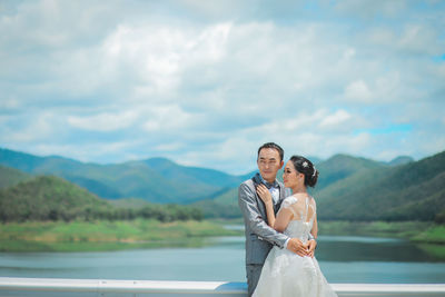 Couple holding camera while standing on landscape