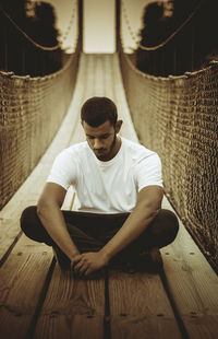 Full length of man meditating on bridge