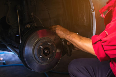 Midsection of mechanic repairing car