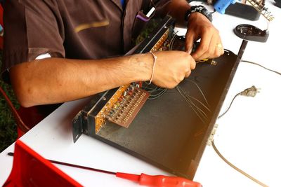 Midsection of man repairing computer part in workshop