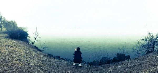 Rear view of man on water against sky