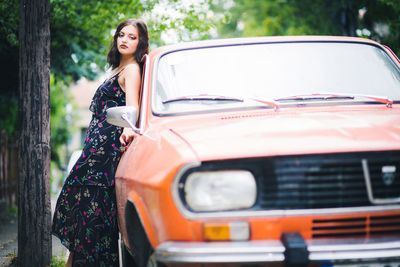 Portrait of smiling woman standing by car