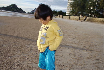 Boy standing on beach against sky