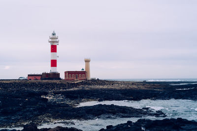 Lighthouse by sea against sky