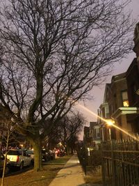 Illuminated street amidst buildings against sky at night