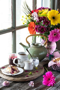 Tea and scones with a beautiful flower arrangement in behind, on a rustic table.