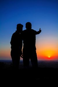 Silhouette couple standing on beach against clear sky during sunset