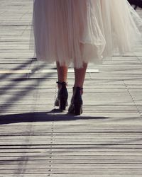 Low section of woman in high heels standing on wooden bridge