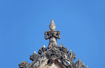 Deity sculpture on the pediment top of the old ordination hall of wat chomphuwek temple,  thailand