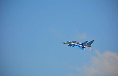 Low angle view of airplane flying against clear blue sky